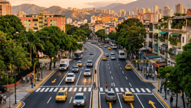 Busy boulevard with taxis, buses, pedestrians, buildings, and mountains at sunset